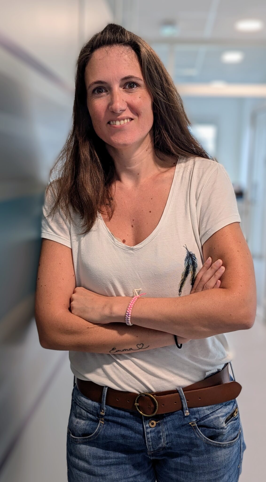 Femme souriante en t-shirt blanc et jeans.